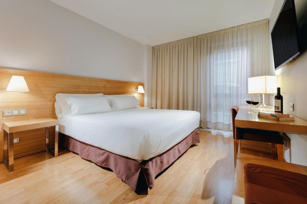 萨拉戈萨Hesperia Zaragoza Centro的酒店客房设有一张大床和一张书桌。