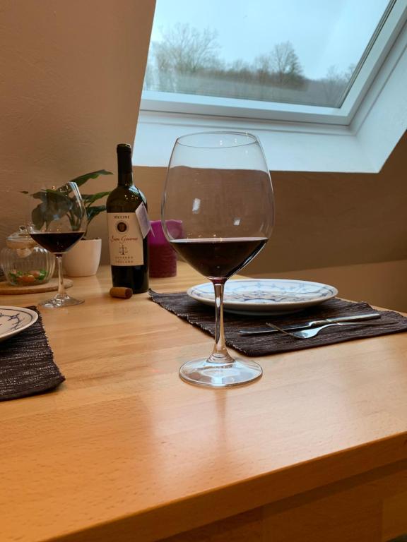 萨尔布吕肯DIE Mansarde !的木桌旁的一杯葡萄酒
