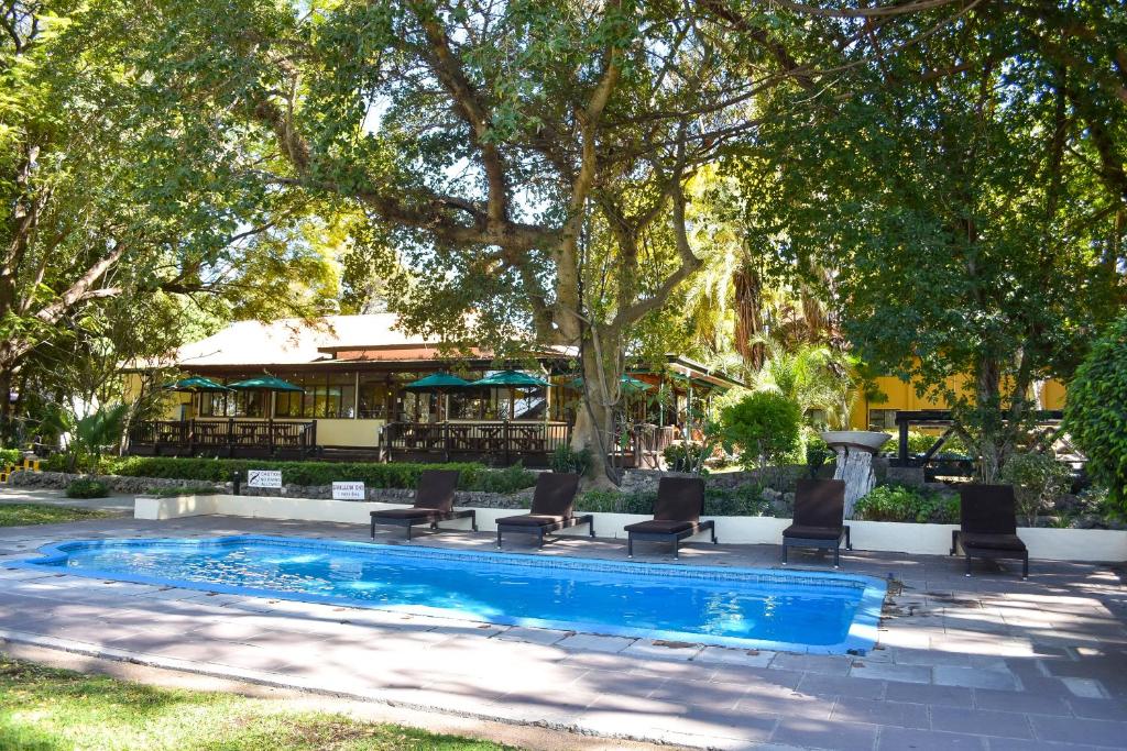 马翁莱利克雷斯塔酒店的一个带椅子和桌子的游泳池以及树木