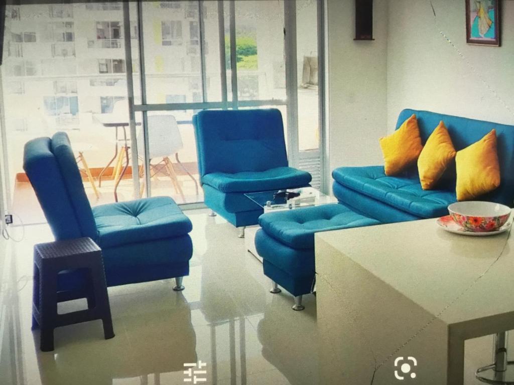 吉拉尔多特Condominio peñazul la morada lo mejor的一间设有三把蓝色椅子和一张桌子的房间