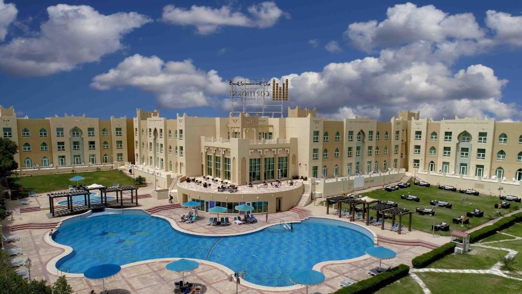 科威特Copthorne Al Jahra Hotel & Resort的一座位于大楼前方的带大型游泳池的度假村
