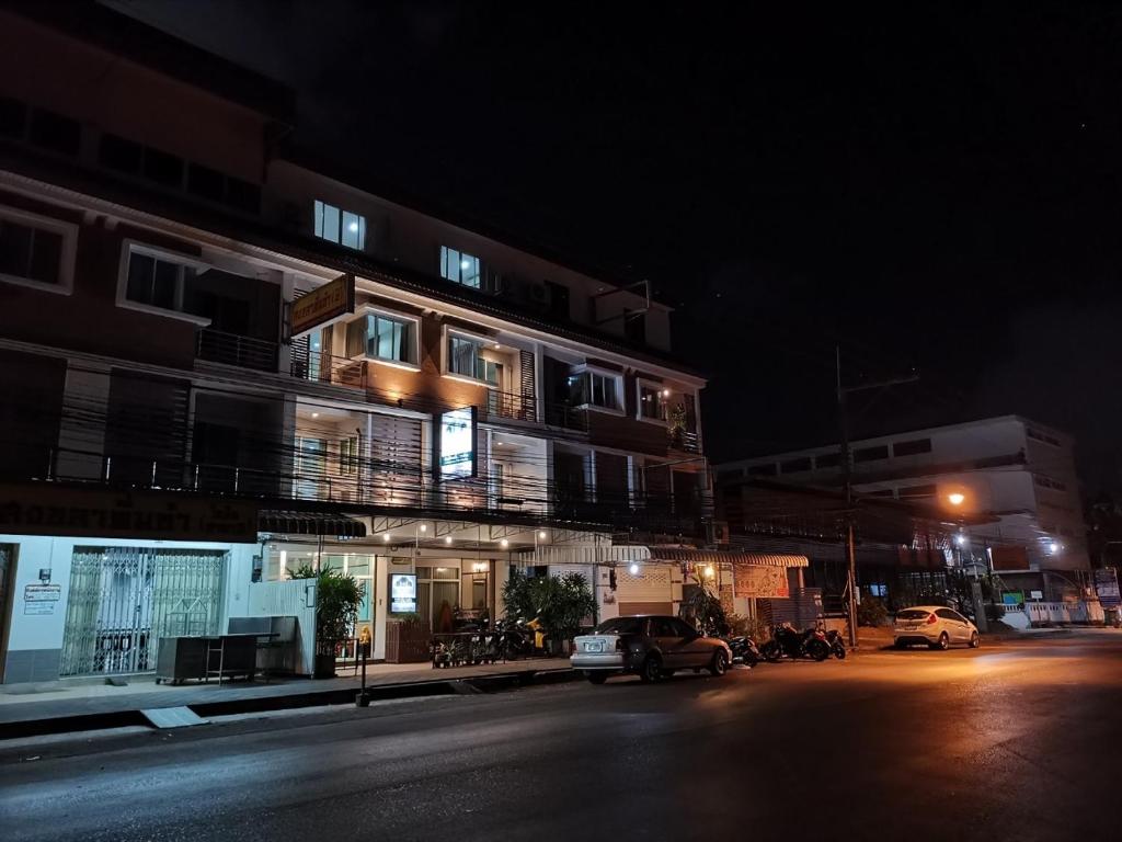 宋卡Ban Kaew Guesthouse Songkhla的一座有汽车在晚上停在街上的建筑