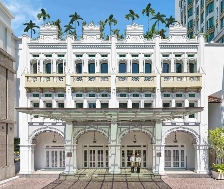 新加坡InterContinental Singapore, an IHG Hotel的一座白色的建筑,前面有两个人