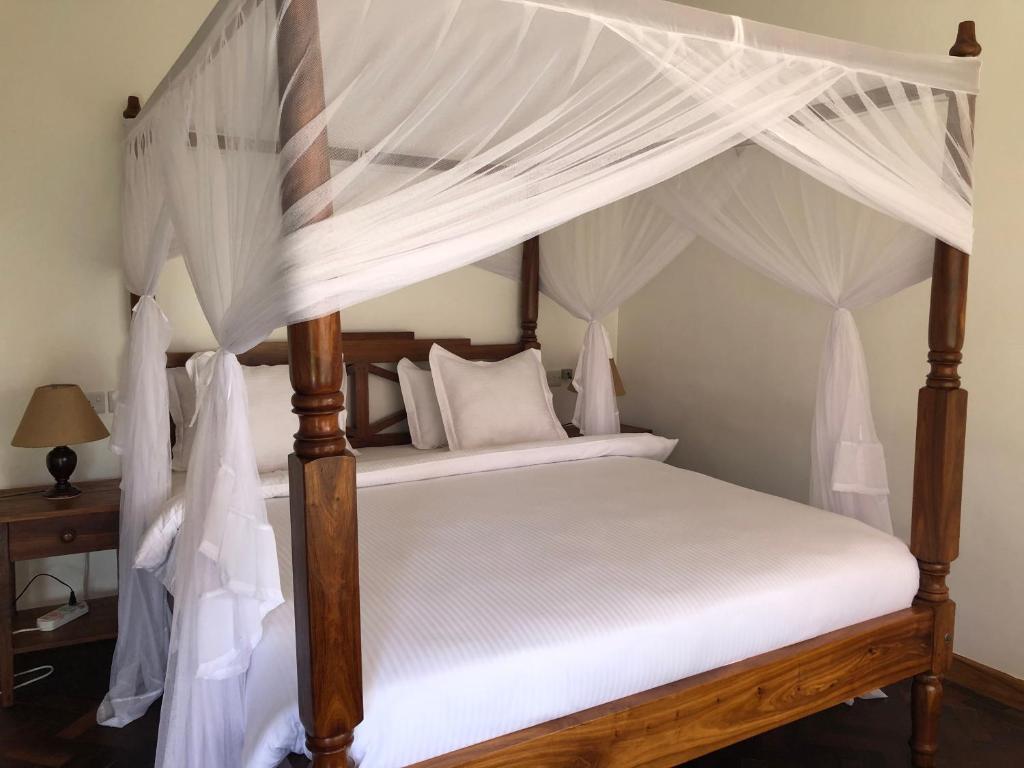 阿鲁沙Bird of Paradise Eco Lodge的卧室配有带白色窗帘的天蓬床
