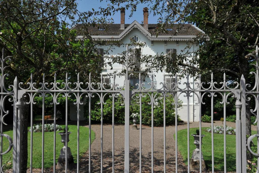 龙尚多特花园酒店的白色房子前面的金属栅栏