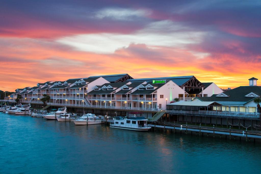 印第安盐滩Holiday Inn & Suites Clearwater Beach S-Harbourside的日落时分停靠在码头的一组船