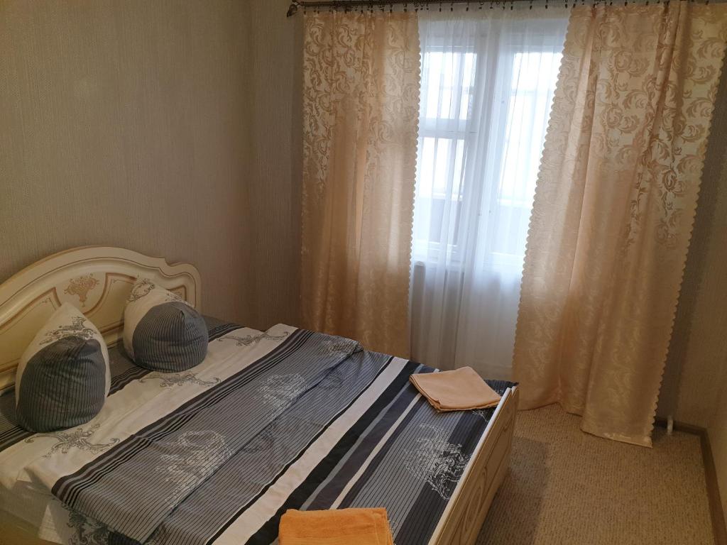 科布林Apartment on 700-letiya Kobrina 4的一间卧室配有床和带窗帘的窗户