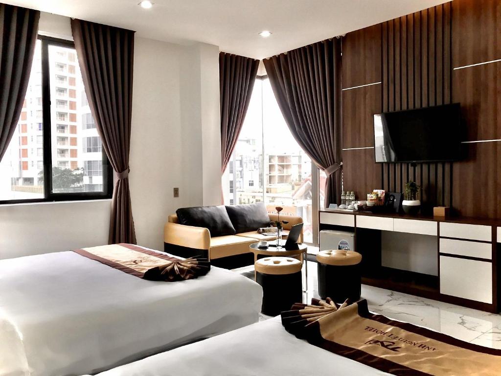 岘港Anh Nguyet Da Nang Hotel的酒店客房,设有两张床和一张沙发