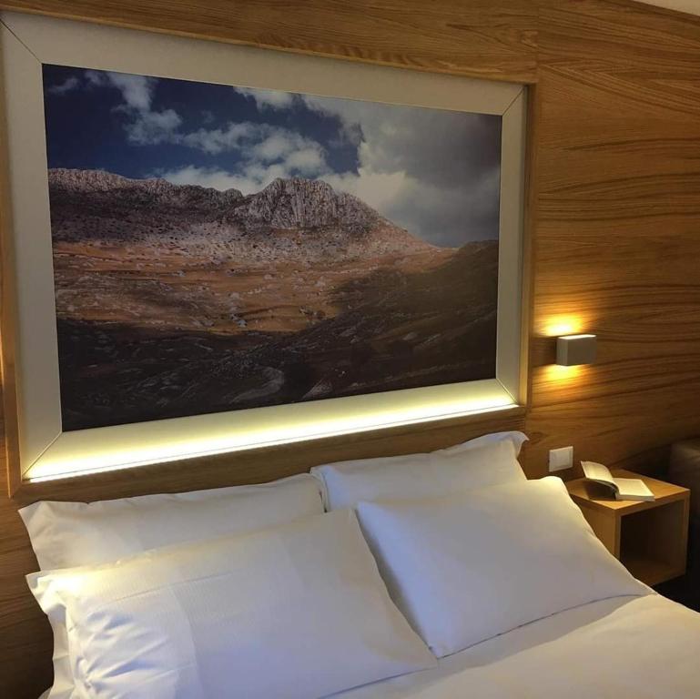 蒙特堡Hotel Miramonti的卧室配有白色枕头,床上方有绘画作品
