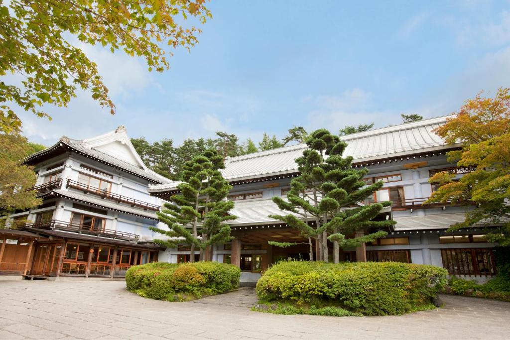 草津Kusatsu Onsen Kusatsu Hotel1913的前面有两棵树的建筑