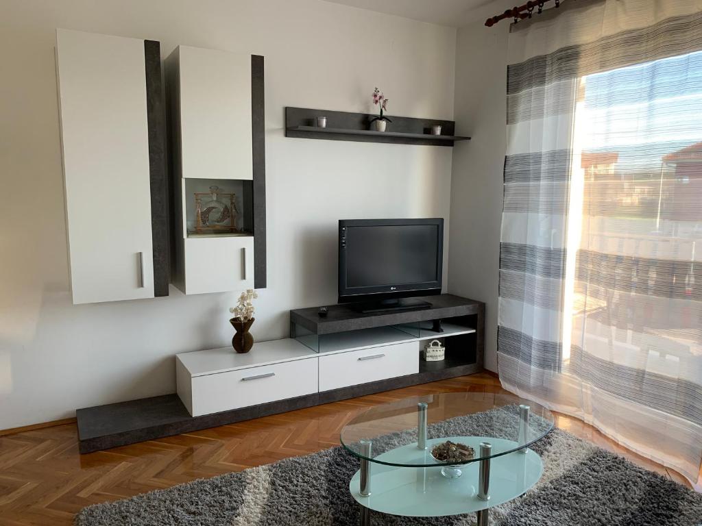 赛斯韦泰Apartman MADAPE的一间带电视和玻璃桌的客厅