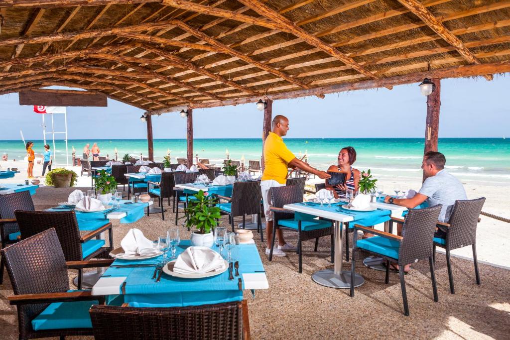 米多恩Palm Beach Club Marmara Djerba的一群坐在海滩桌子上的人