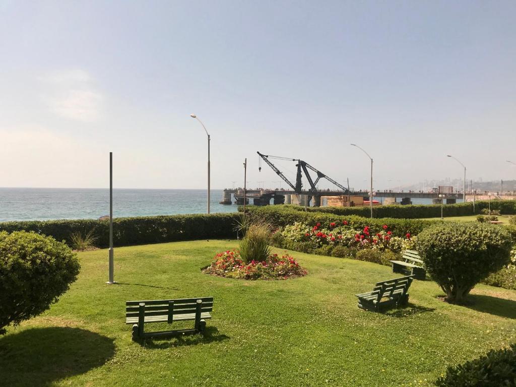 维纳德马Departamento en Playa Acapulco viña del mar的两个长椅坐在靠近海洋的公园里