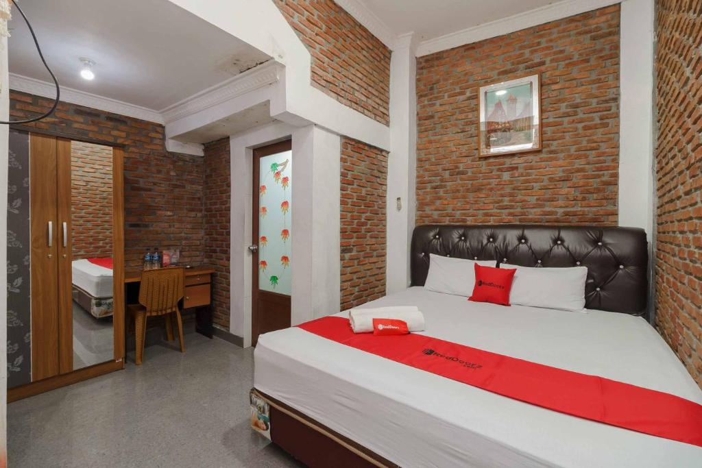 先达RedDoorz Syariah near Jalan Asahan Pematang Siantar的一间卧室设有一张带砖墙的大床