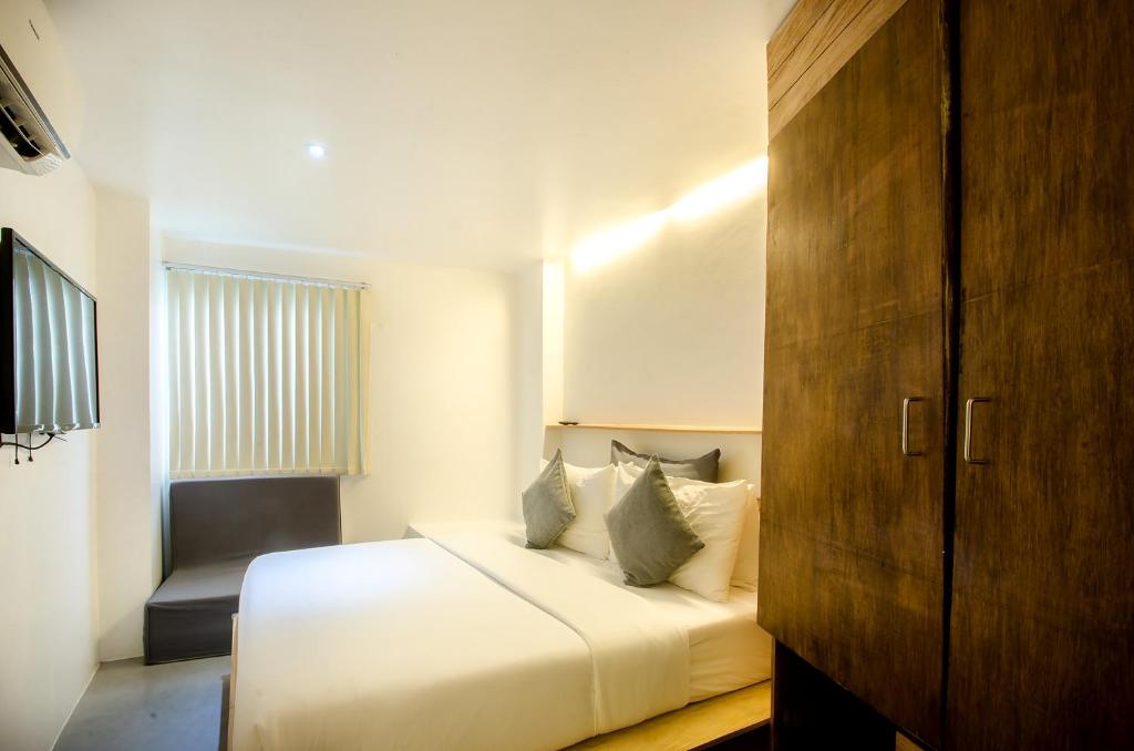 长滩岛速淑尼精品酒店的卧室配有白色的床和椅子