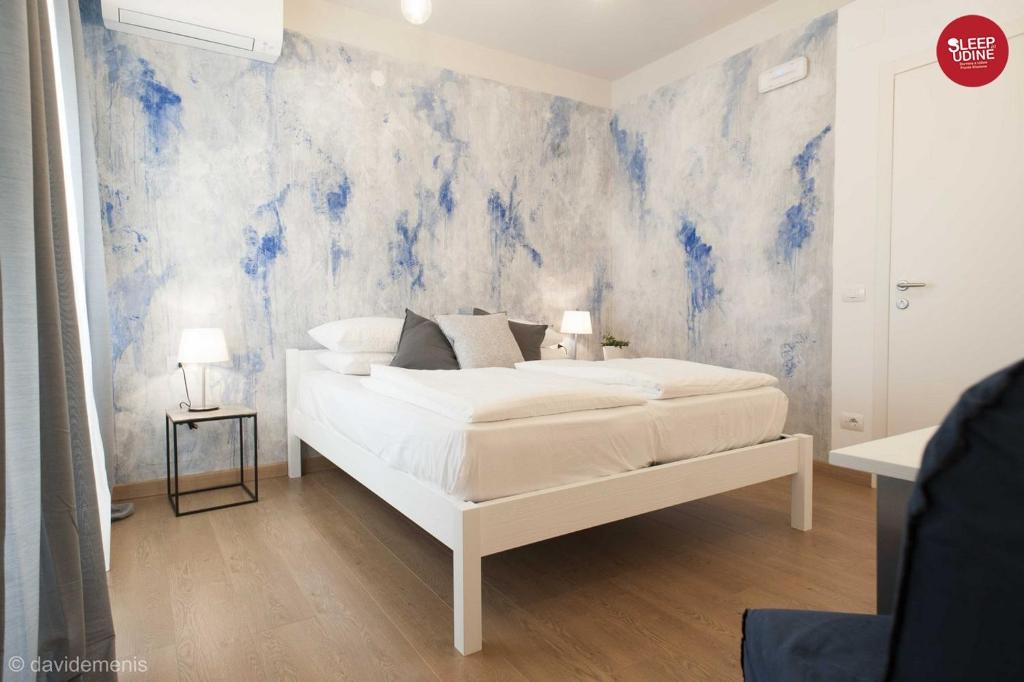 乌迪内Sleep In Udine的卧室配有白色的床和蓝色的墙壁