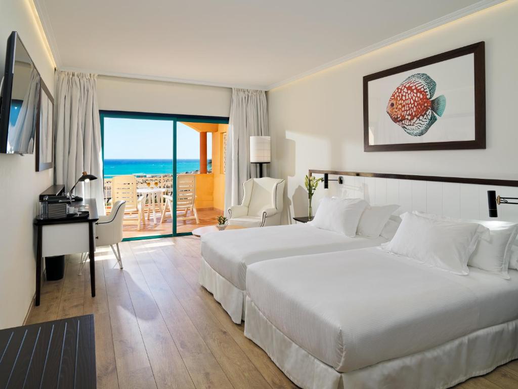 科斯塔卡玛H10 Playa Esmeralda - Adults Only的酒店客房设有两张床和一张书桌,享有美景。