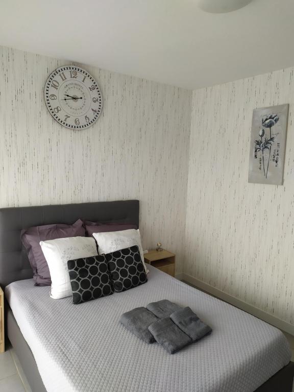 桑斯Zen attitude Appt 127的卧室配有一张挂在墙上的带时钟的床
