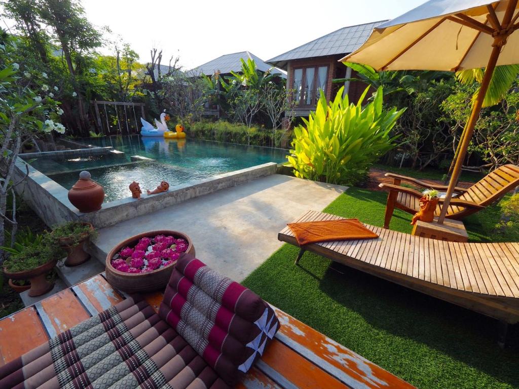 素可泰BaanSuk Sukhothai Resort的后院设有带沙发和椅子的游泳池