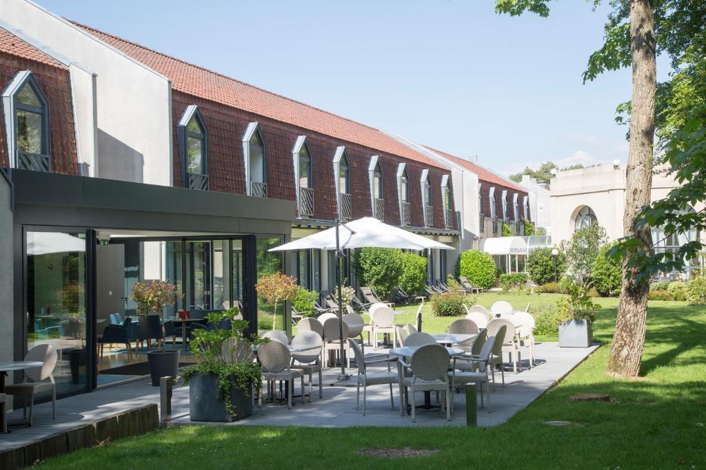 勒图凯-巴黎普拉日勒图凯假日酒店度假村的一座配有白色桌椅的庭院和一座建筑
