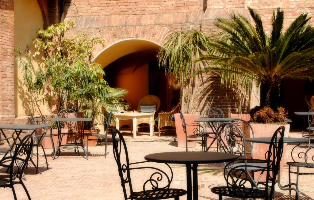 锡耶纳洋红寺院酒店的户外庭院设有桌椅和植物