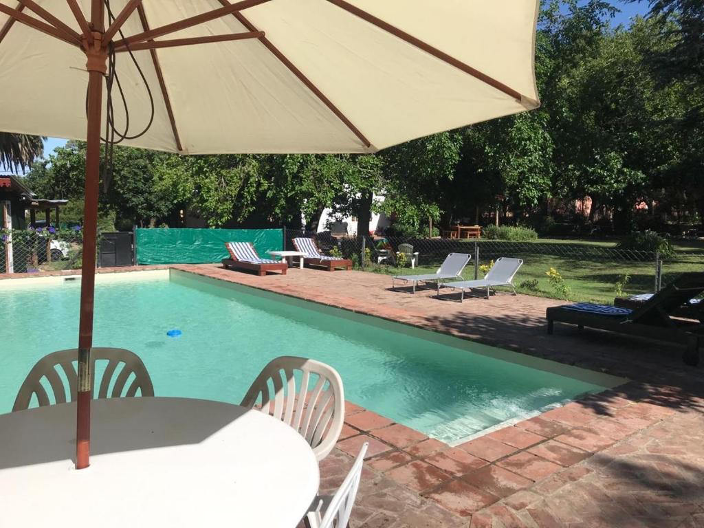 圣哈维尔Posada El Cortijo的游泳池旁带遮阳伞的桌子
