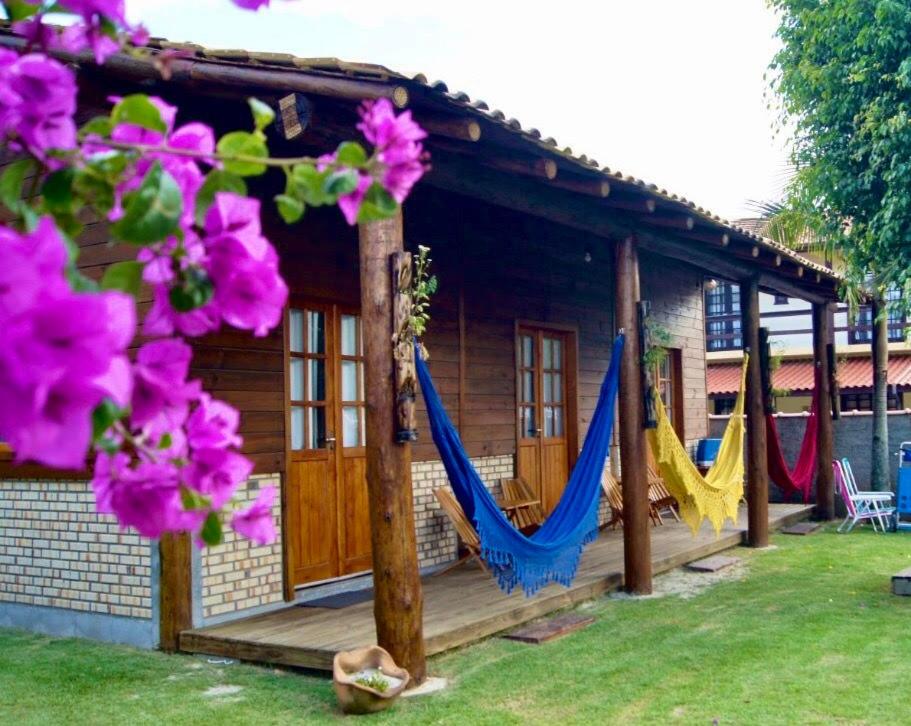 瓜尔达恩巴Mandala Chalés的一座房子前面有吊床,鲜花盛开