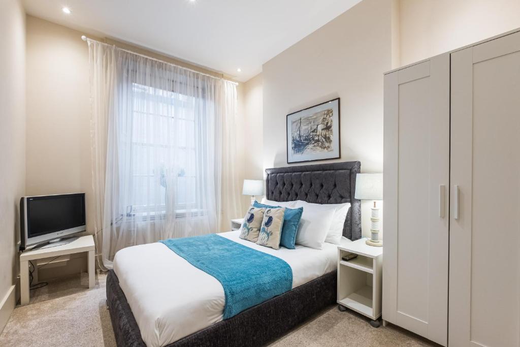 伦敦艾丽西亚南肯辛顿公寓的一间卧室配有一张大床和电视