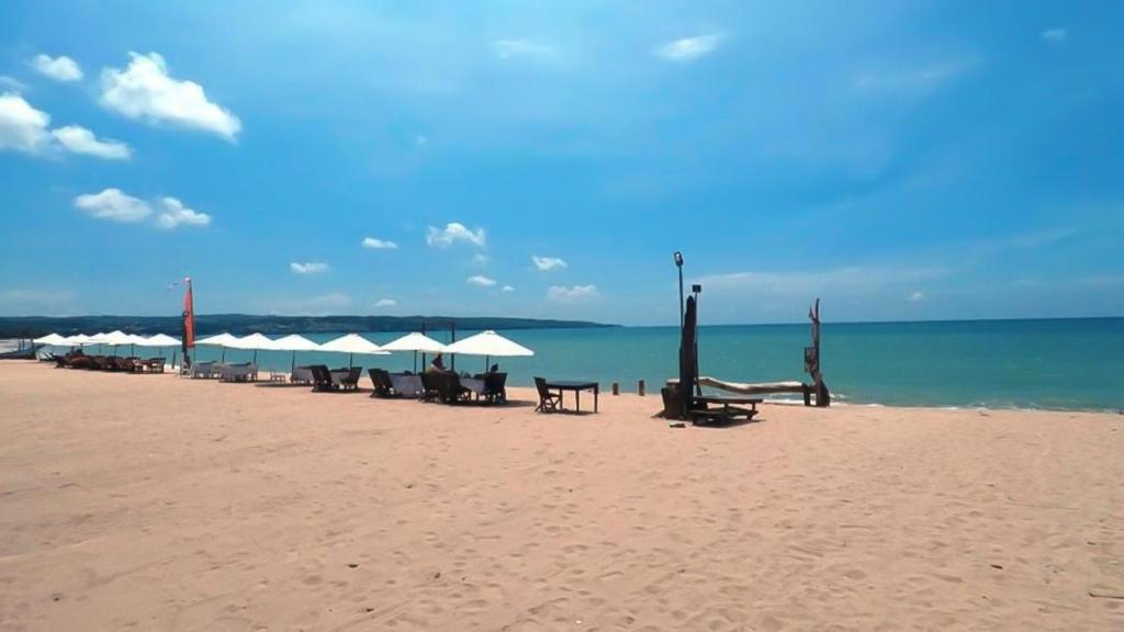 金巴兰金巴兰快乐别墅的海滩上设有椅子和遮阳伞,还有大海