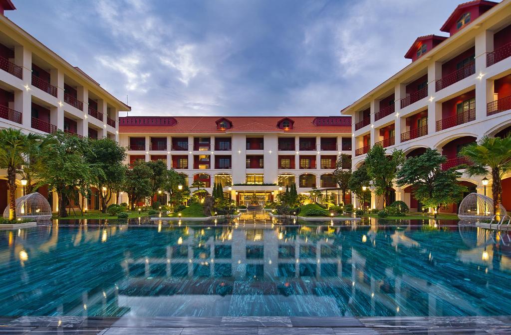 顺化Senna Hue Hotel的大楼前设有大型游泳池的酒店