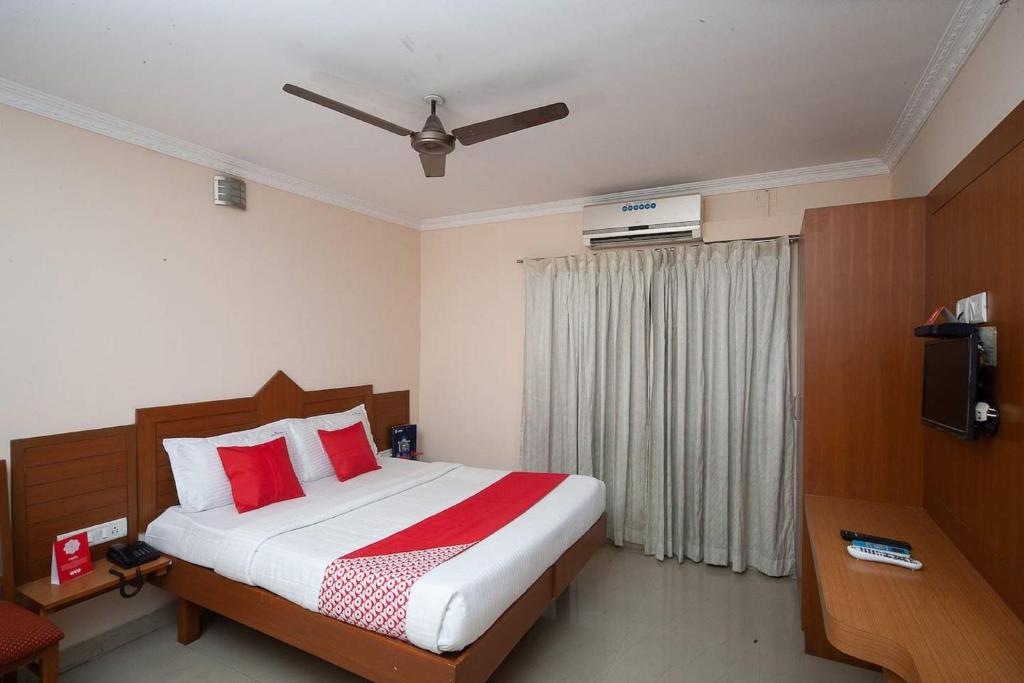 钦奈Silver Cloud Hotel Sholinganallur的一间卧室配有一张带红色枕头的床和电视。