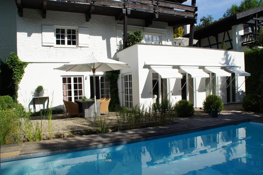 奥伯斯特多夫Landhaus am Plattenbichl - Luxus Apartment mit Privat-Pool und Sauna - im Sommer Bergbahn inklusive的一座带游泳池和遮阳伞的白色房子