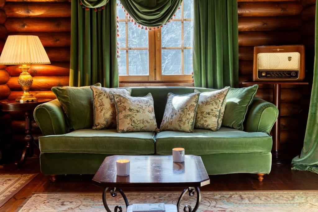 KhrisovítsionAll Seasons Paradise的客厅配有一张绿色沙发,设有一张桌子