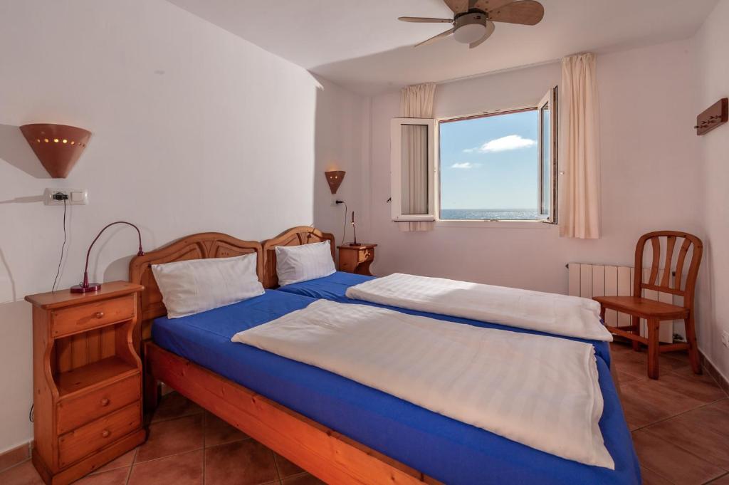 Cala MendiaResidencial Playa Mar的一间卧室配有一张带蓝色床单的床和一扇窗户。
