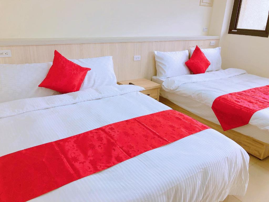 Fengping云山水好栈的配有红色和白色床单的客房内的两张床
