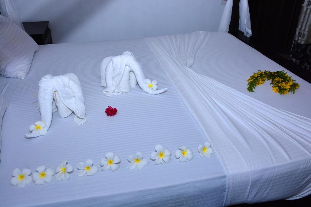 坦加拉Little Sunshine Guest House & Restaurant的一张带白色床单和鲜花的床