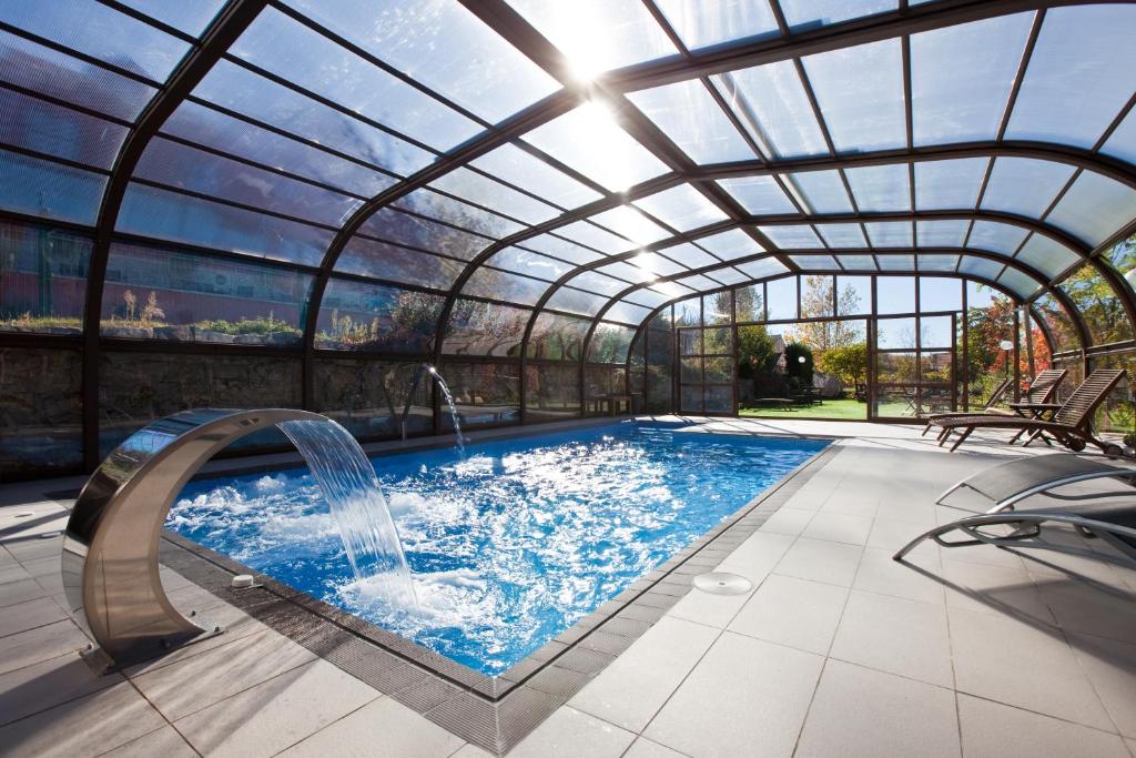 塞尔塞迪利亚勒克斯德尔波尼连酒店的一个带玻璃天花板和水滑梯的室内游泳池
