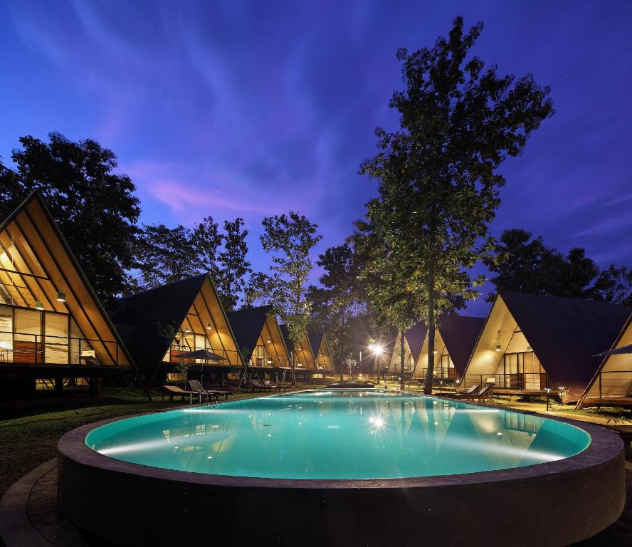 达瓦拉维Kottawatta River Bank Resort的一座游泳池,在晚上在建筑物前
