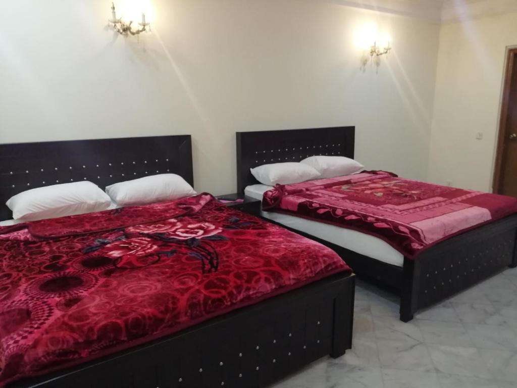 拉合尔Star Hotel Lahore的两张睡床彼此相邻,位于一个房间里