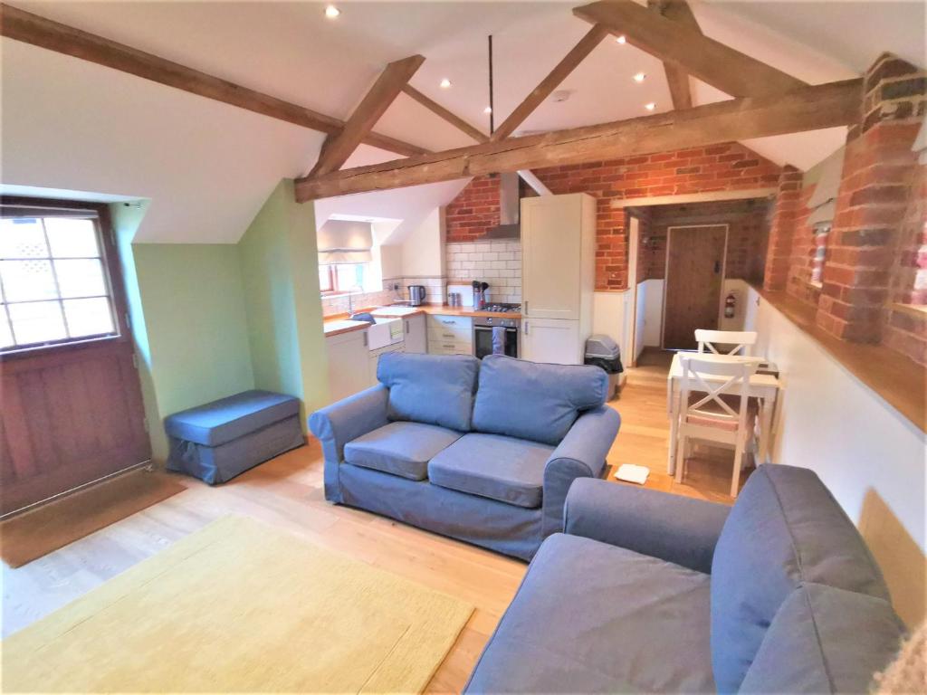 灵伍德Blashford Manor Farmhouse - New Forest Cottage的一间带蓝色沙发的客厅和一间厨房
