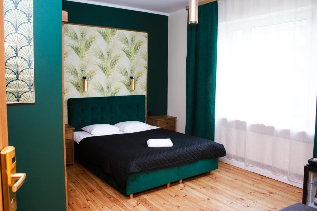 波兹南Elegant Apartments的一间卧室配有一张带绿色床头板的床