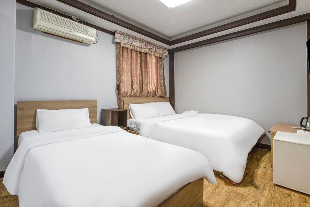 首尔柯姆康汽车旅馆的配有白色床单的客房内的两张床