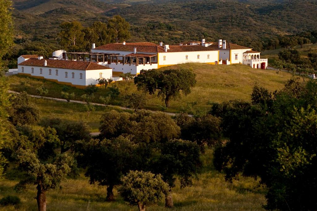 巴兰科斯Parque de Natureza de Noudar的一座树木茂密的山丘上的白色大房子