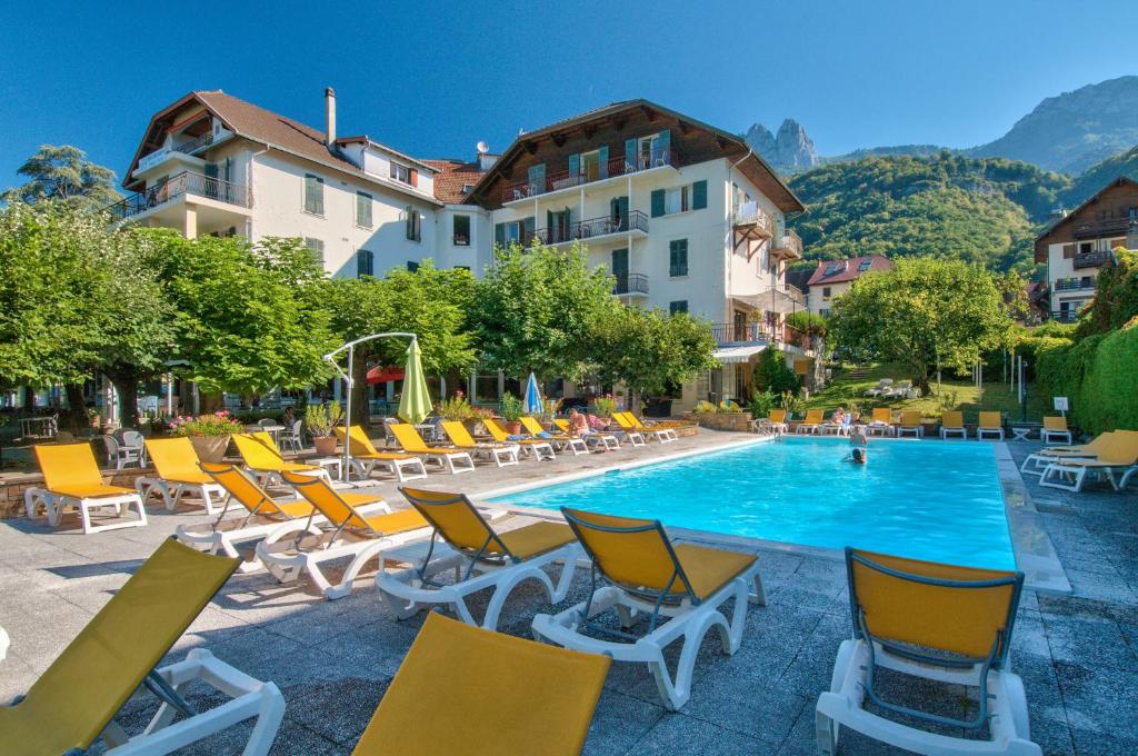 塔卢瓦尔杜拉克酒店的一座带椅子的游泳池和一座建筑的酒店