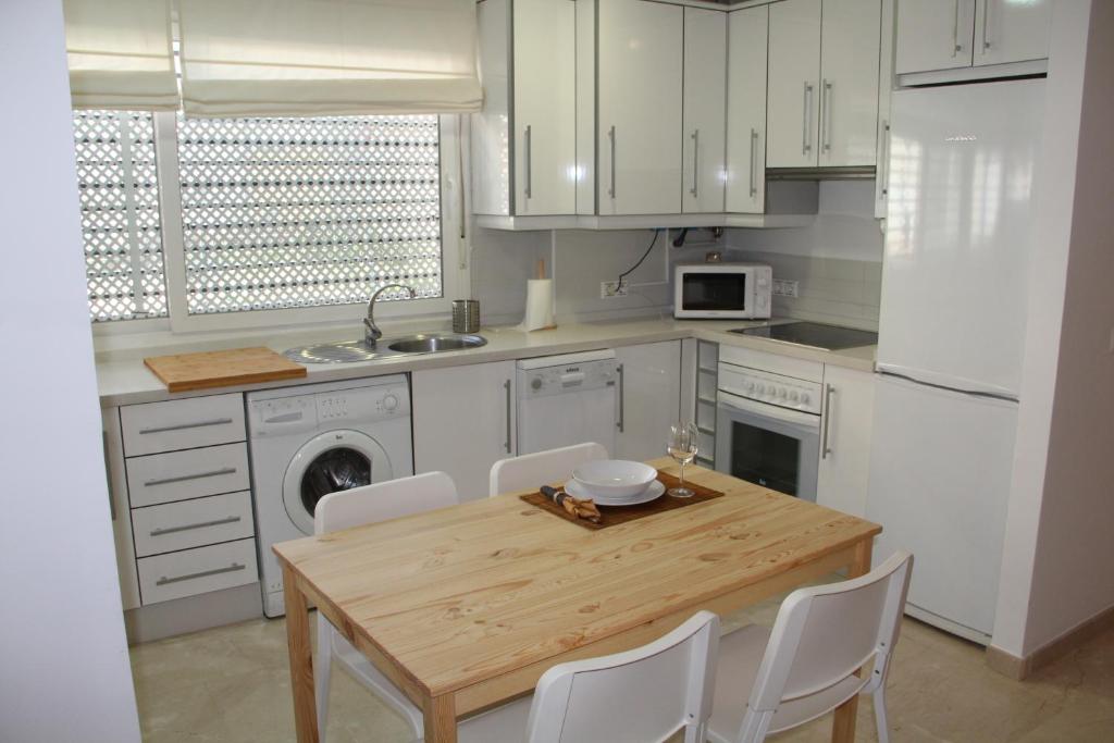 科尔多瓦Apartamento Iris的厨房配有木桌和白色橱柜。