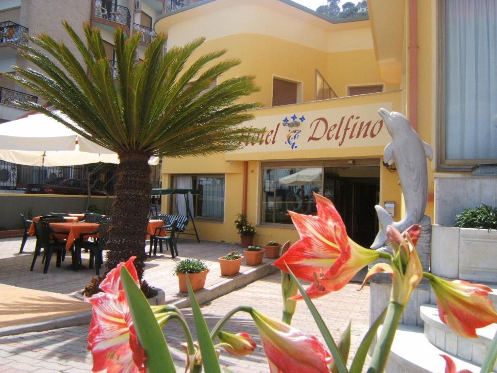 莱圭利亚Hotel Delfino的一座楼前有棕榈树的餐厅
