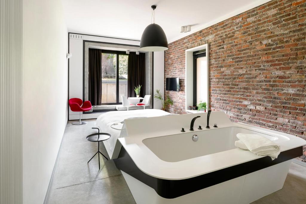 Opglabbeek超越住宿加早餐酒店的浴室设有大型白色浴缸,毗邻砖墙