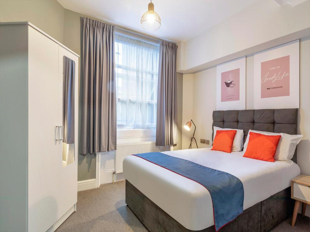 伦敦Townhouse Apollo, Hyde Park的一间卧室配有一张带橙色和蓝色枕头的大床