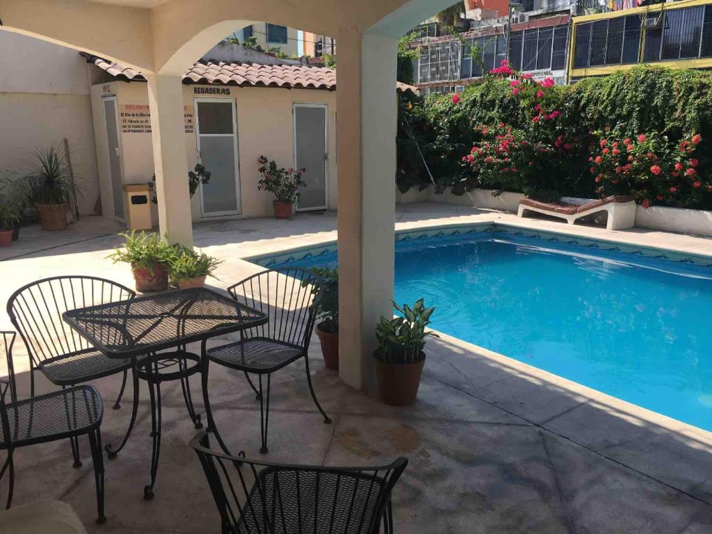 阿卡普尔科Hotel magallanes con cocineta 100 Metros de playa的游泳池旁带桌椅的天井
