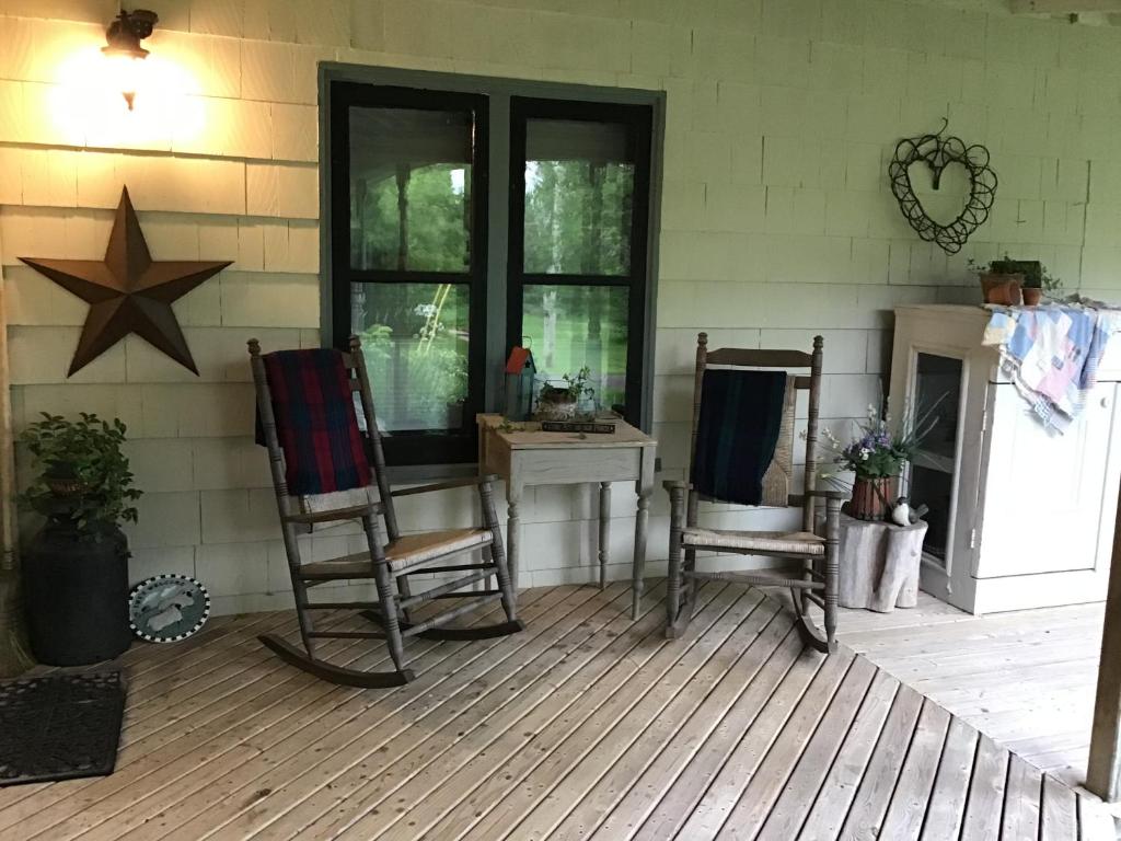 萨默赛德Guest Suites at Willowgreen Farm的门廊配有两张摇椅和一张桌子